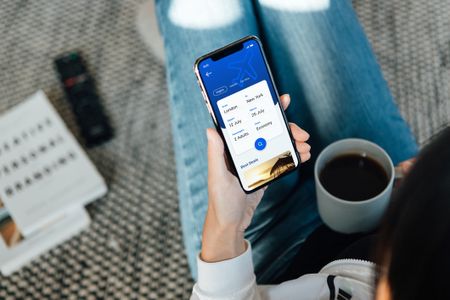 a woman browsing flights on her smartphone, using an unspecified travel app