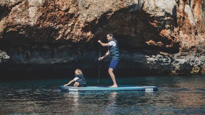 Best inflatable paddle boards: Three people walking up the beach holding Red Paddle Co inflatable paddle boards