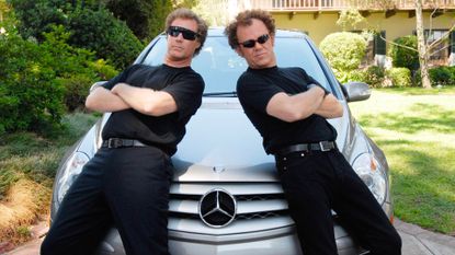 Will Ferrel and John C Reilly lean on the bonnet of a car while wearing glasse