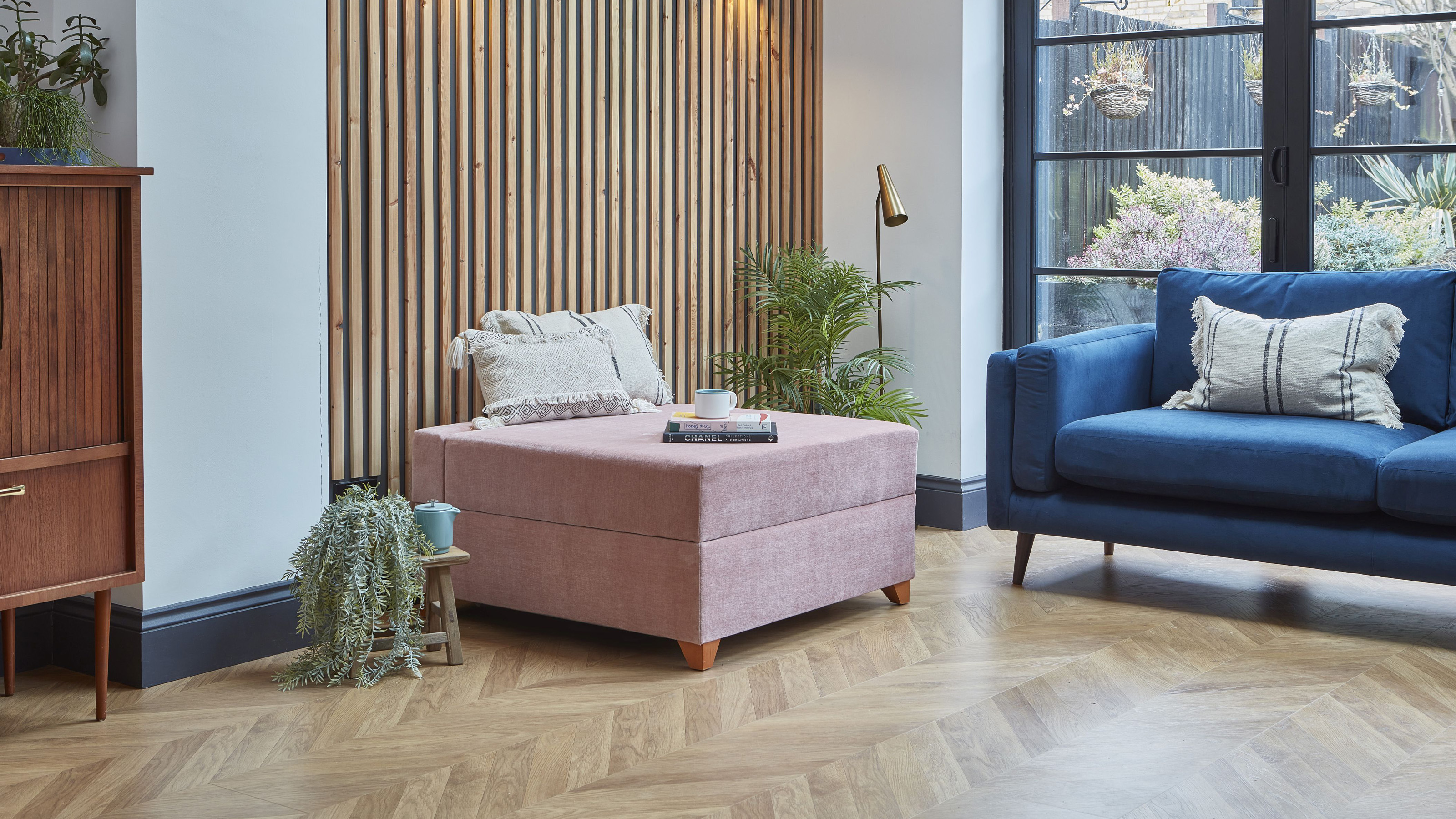 Darlings of Chelsea pink bed-in-a-box in a living room with a wooden parquet floor