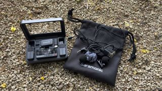 Shot of the complete kit, including the charging case holding the mics and receiver, plus a draw-string bag which holds two lavalier clip mics and wind shields