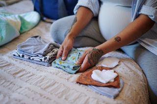 A pregnant woman folding baby clothes