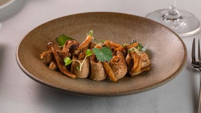 wild mushroom pate with pickled mushrooms served on a plate with garnish