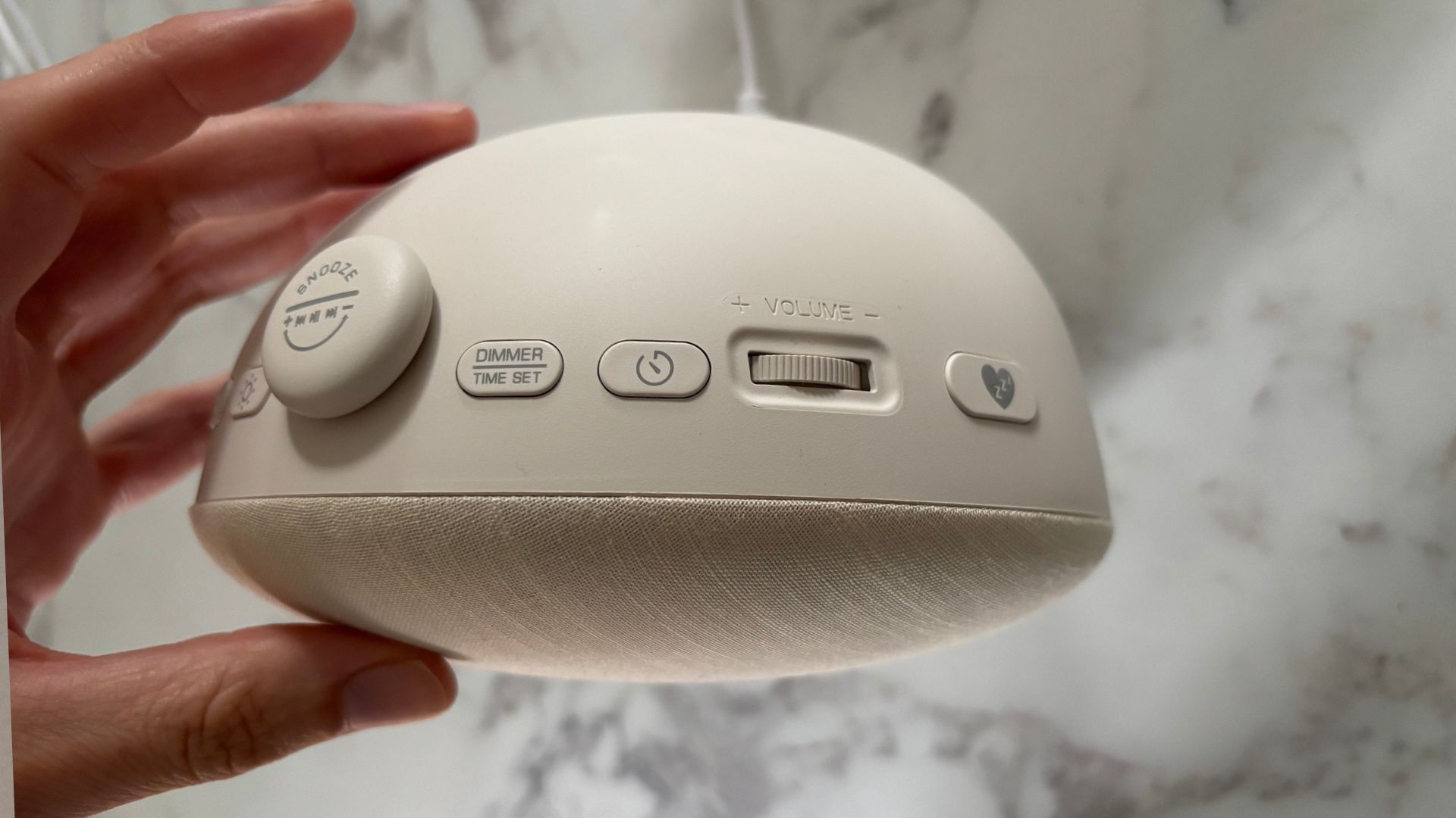 The image shows a hand reaching for the control buttons of the Dreamegg Sunrise 2 alarm clock