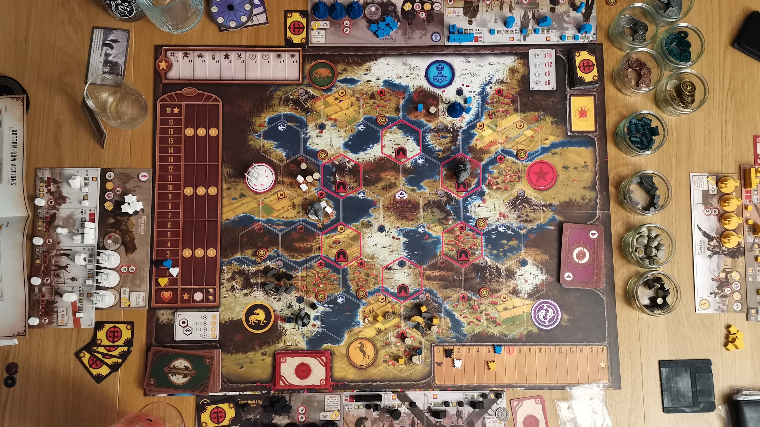 An overhead view of the Scythe board with tokens and components laid out on a wooden surface