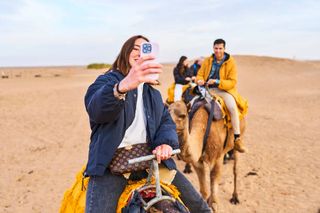 A woman taking a selfie on a camel in Morocco.