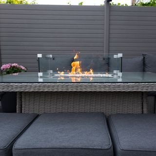 Gas-fired table patio heater surrounded by grey cushioned seating in garden