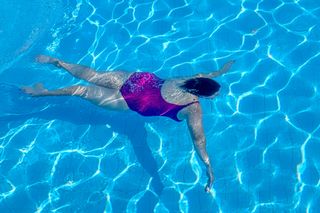 Person swimming underwater in pool
