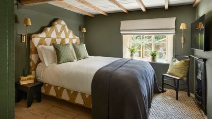 hotel chic style bedroom in a country cottage with dark walls and beamed ceiling