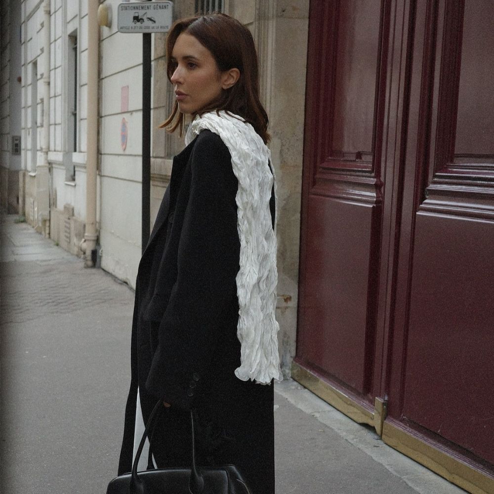 A woman in Paris wearing an autumnal outfit standing in front of a burgundy door