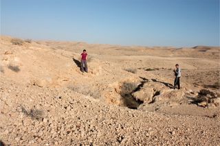 Researchers stand near the entrance of Ashalim Cave, where they found the lead artifact.