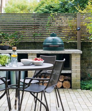 dining table in front of an outdoor cooking area with big green egg cooker