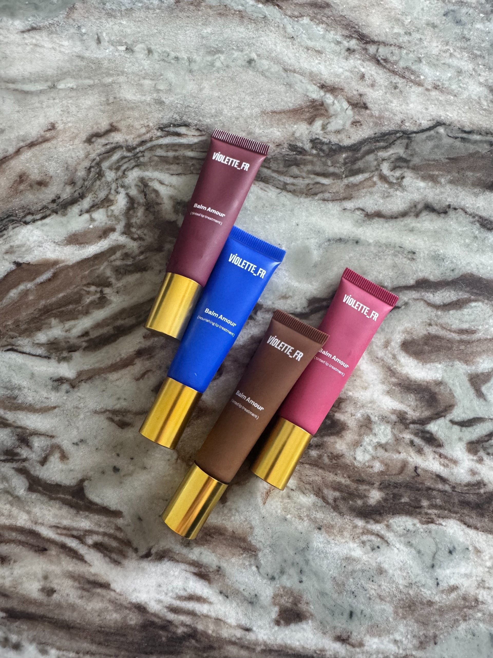 The four Violette_FR Balm Amour lip balm shades on a marble table