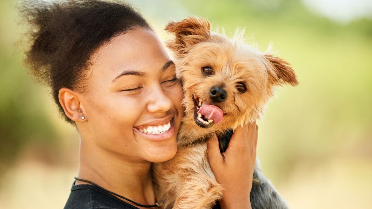 Smiling woman hugging her dog outside