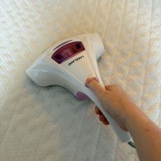 Mattress vacuum on a mattress with hand holding it