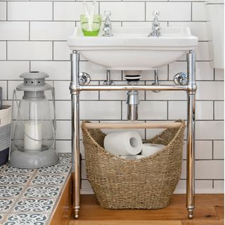 white wall tiles, wood flooring and a raised step, basin and metal frame washstand and woven basket