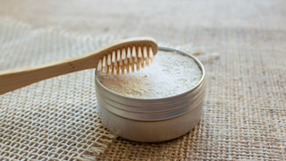 Pot of baking soda next to a wooden toothbrush