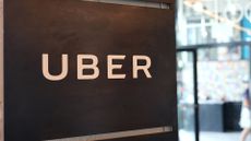 Uber logo pictured on a wall at the Falchi Building in New York City, with pedestrian walking by on the street outside.