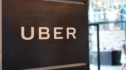 Uber logo pictured on a wall at the Falchi Building in New York City, with pedestrian walking by on the street outside.