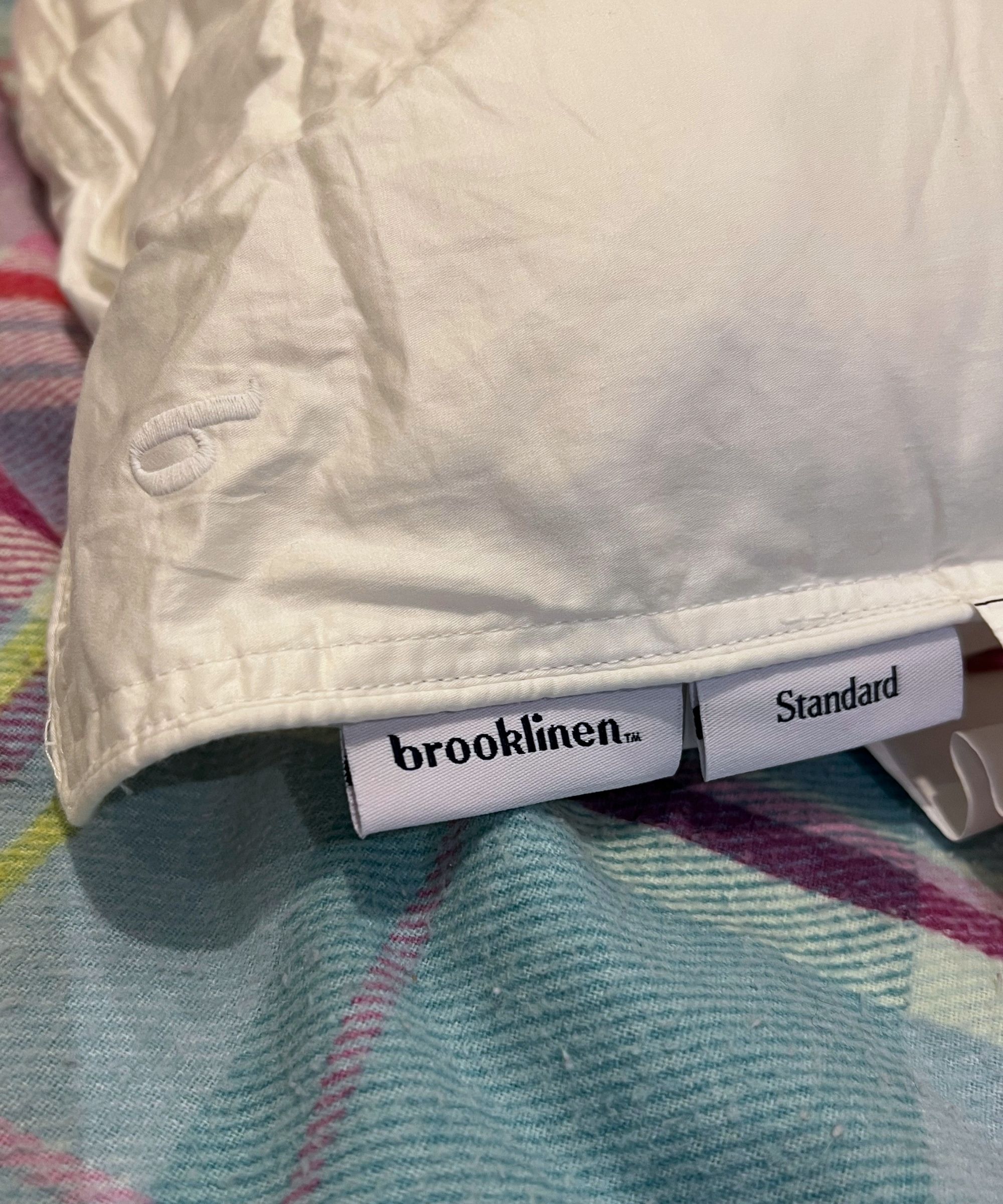 Brooklinen down alternative pillow on a colorful plaid bedspread