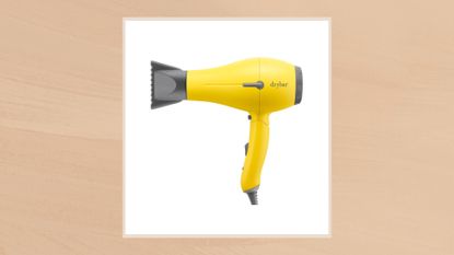 An image of the Drybar Baby Buttercup Travel Blow-Dryer in a taupe frame set against a beige watercolour-style background