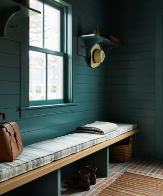 mudroom with teal cladding walls and bench with striped cushion