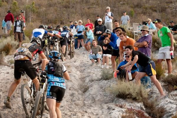 Local crowds cheer on the riders as they climb a steep sandy section