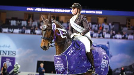 Female dressage rider Becky Moody wears her winners sash as she rides Jagerbomb, wearing his winner's rosette and rug on their lap of honour
