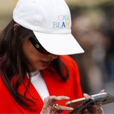 Woman wearing a cap, one her phone with a gelcare-like manicure