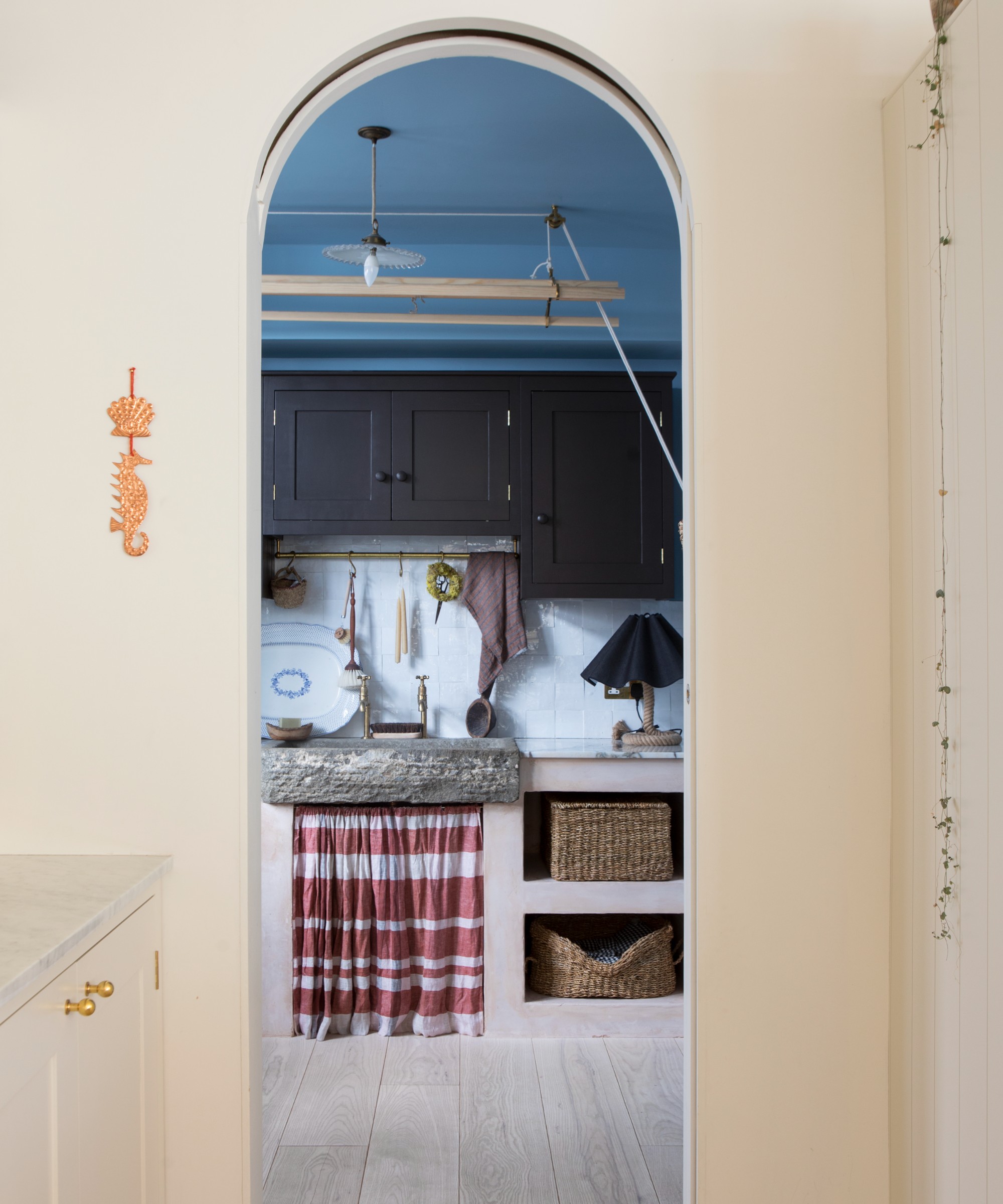 A magnolia-painted kitchen with an arched doorway leading into a utility room with a blue ceiling