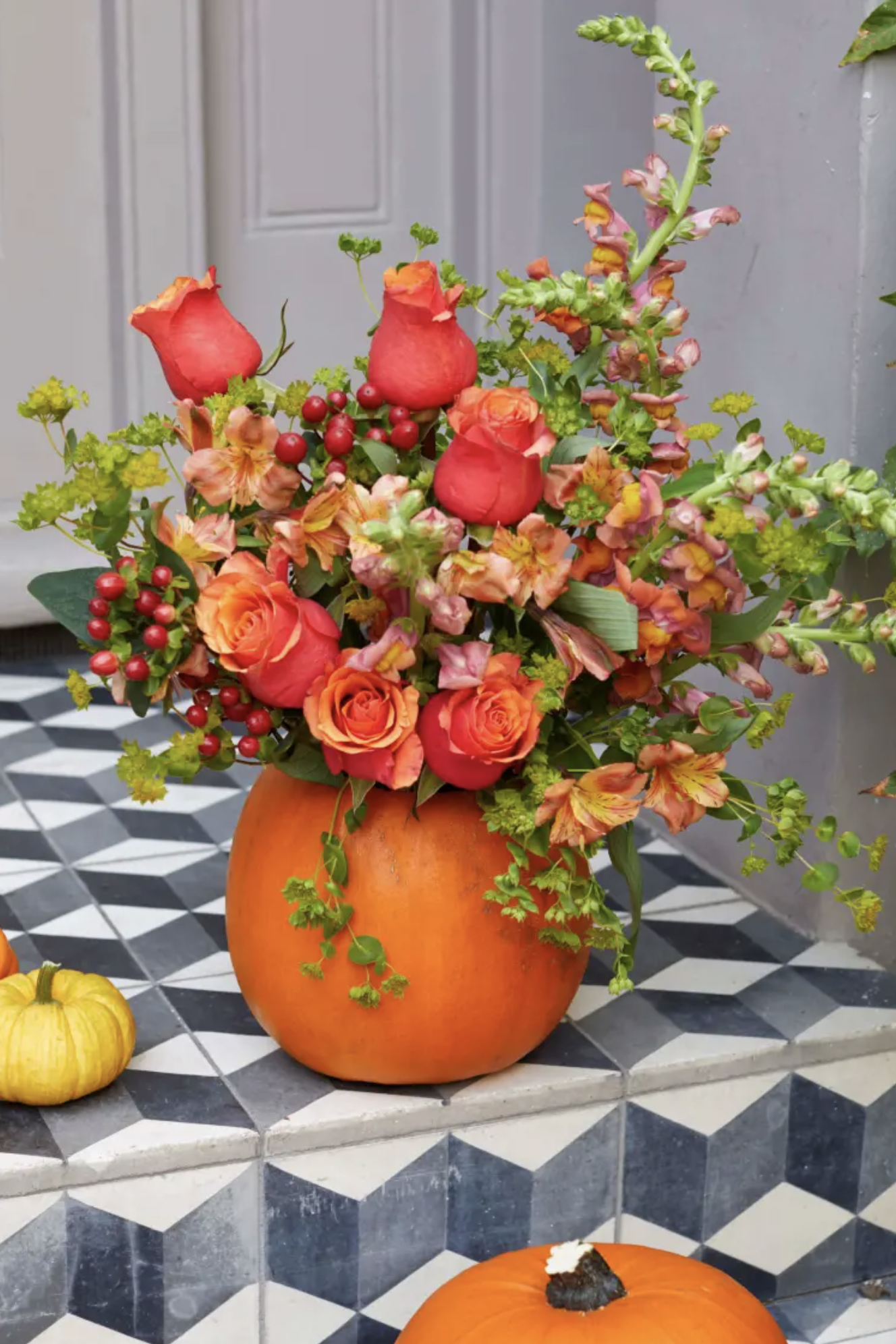 Pumpkins as vases with flower arrangements on a tiled doorstep