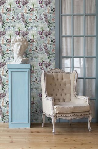 floral wallpaper in living room with cream armchair and bust