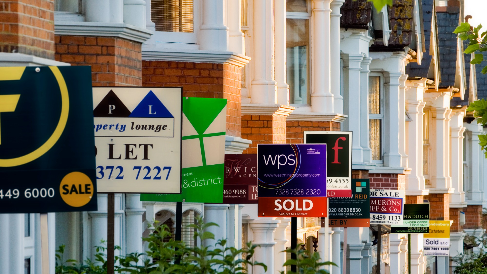 Row of houses with for sale signs in front of them 