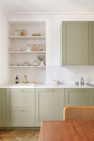 a sage green kitchen with white walls and wooden flooring