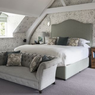 main bedroom with printed walls bed and sofaset with cushions