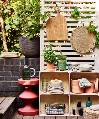 Mini outdoor kitchen set up on wooden fence panel with stacked crates