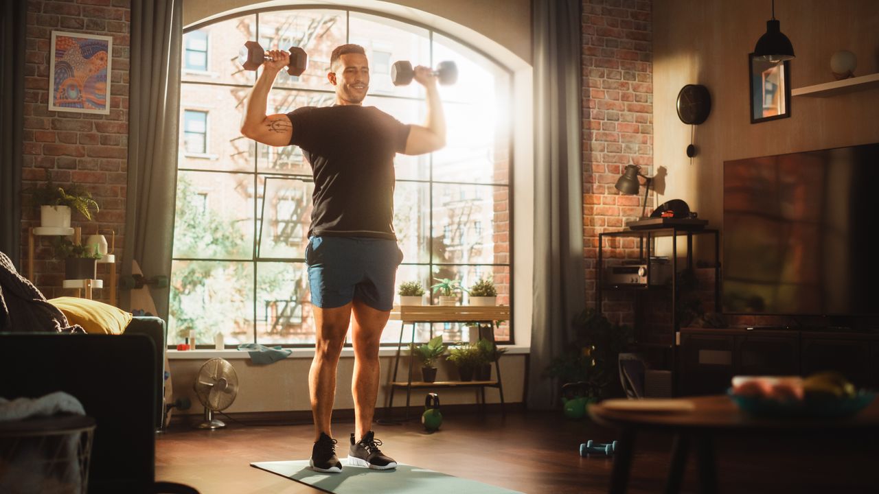 A man performing a dumbbell shoulder press at home