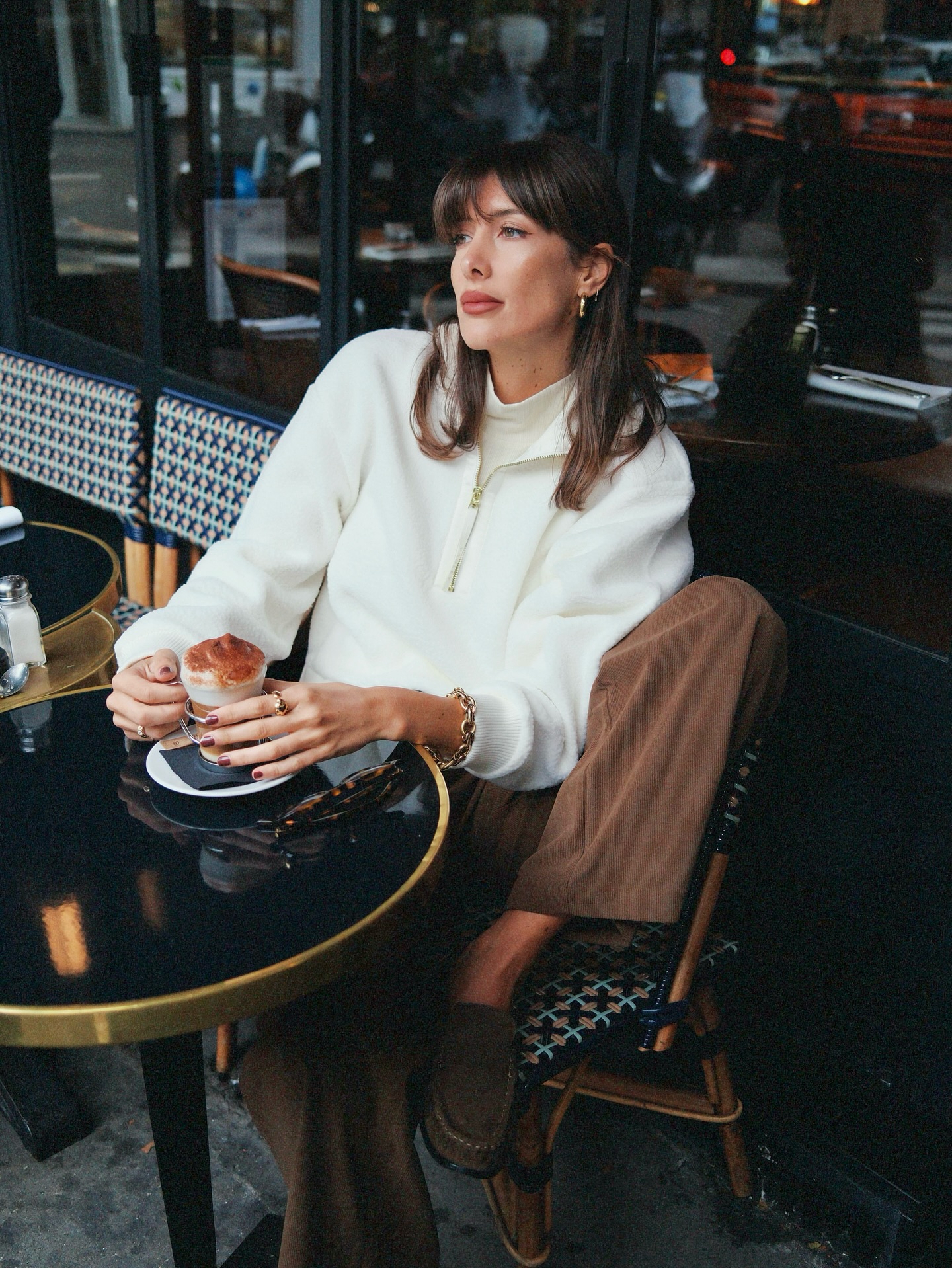 A photo of @juliesfi sitting in a French cafe wearing a white jumper
