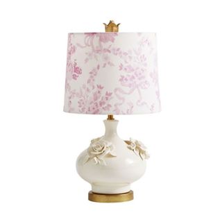 A table lamp with a pink floral linen shade and a cream ceramic base