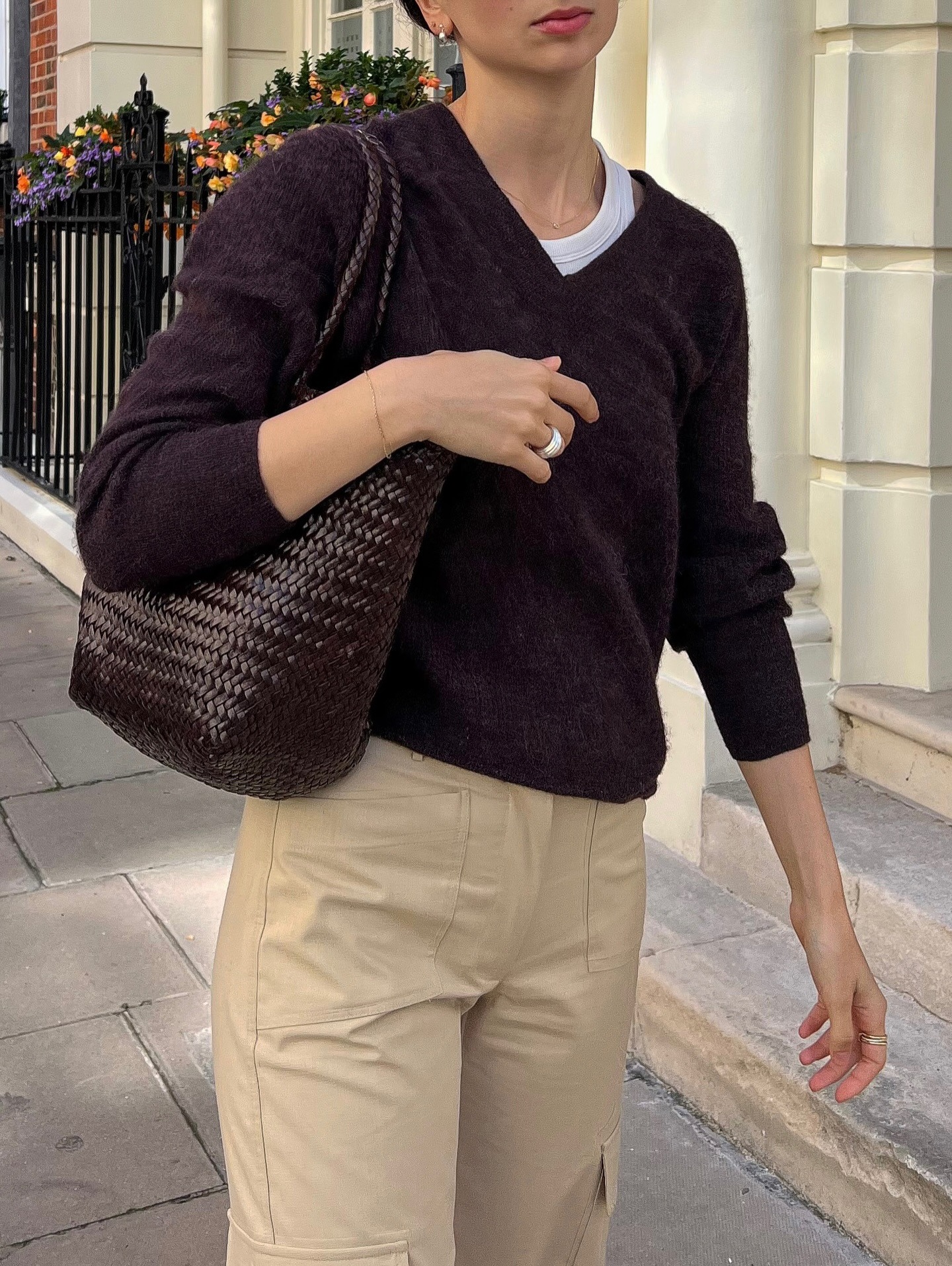 French influencer @pia_mbd wears a v-neck jumper in dark aubergine with beige trousers.