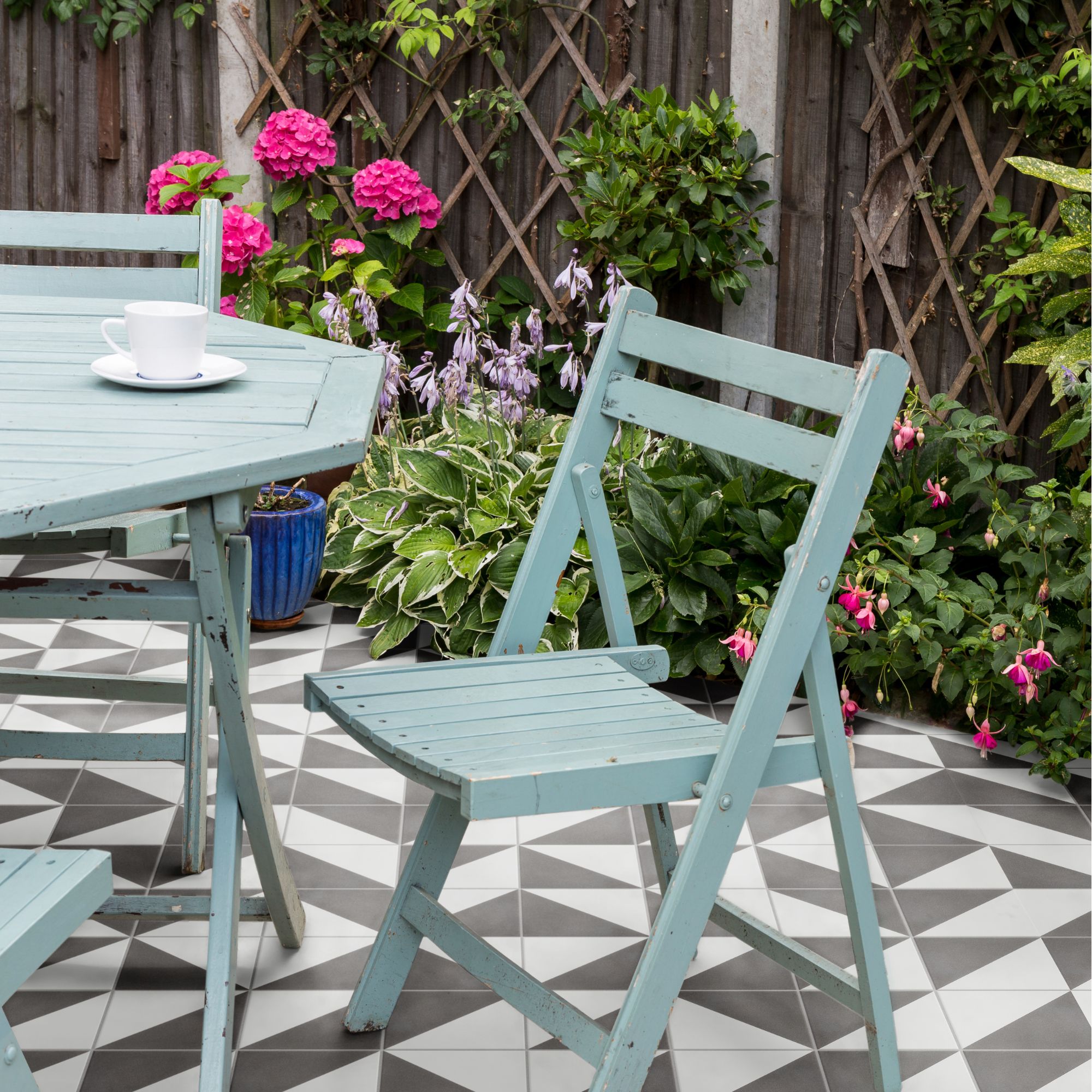 A black and white tiled garden scheme, offset with blue furniture and bright plants