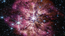 A star shines in the middle of a purple cloud of cosmic dust.