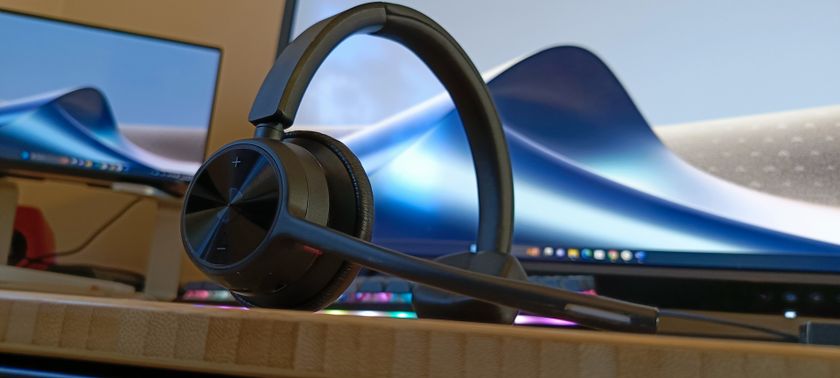 A Poly Voyager 4310 UC headset on a wooden desk