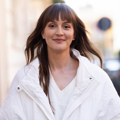 Leighton Meester has long brown hair and bangs while wearing a white V-neck T-shirt and a white jacket, and she poses on the cover of 2014 album Heartstrings