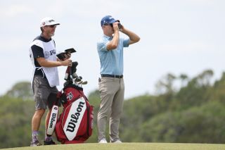 Kevin Streelman uses a rangefinder whilst his caddie stands next to him