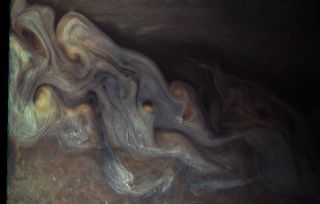 This photo taken by NASA’s Juno spacecraft on May 19, 2017, at 5:50 UTC from an altitude of 5,500 miles (8,900 kilometers) shows high-flying white clouds composed of water ice and/or ammonia ice. In some areas, these clouds appear to form “squall lines” — narrow bands of high winds and storms associated with a cold front.