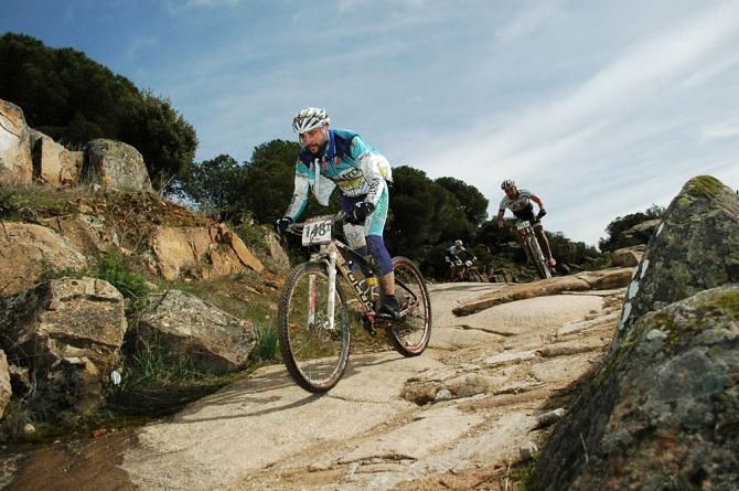 A rider and his teammate on a rock.