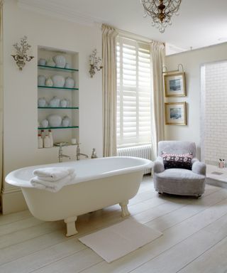 neutral bathroom with pale curtains and upholstered chair