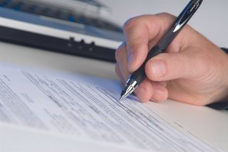 A person signing a form with a pen