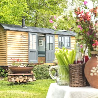 shepherd's hut in garden with firepit